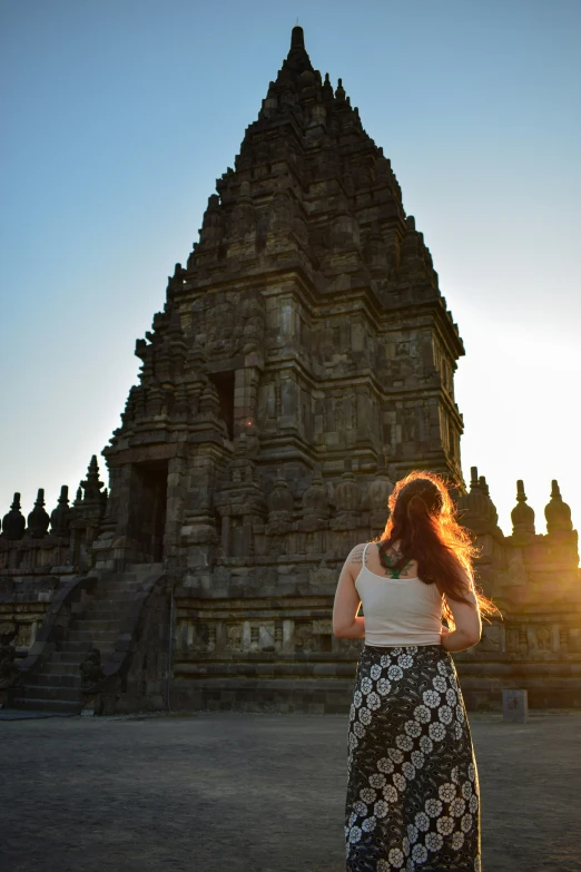 a woman walking by an old stone building with her hair flying