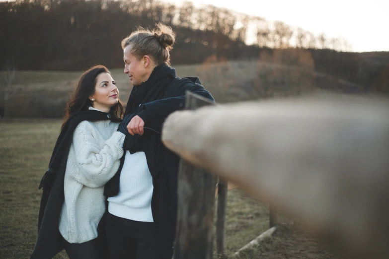 the man and woman are holding hands near a fence