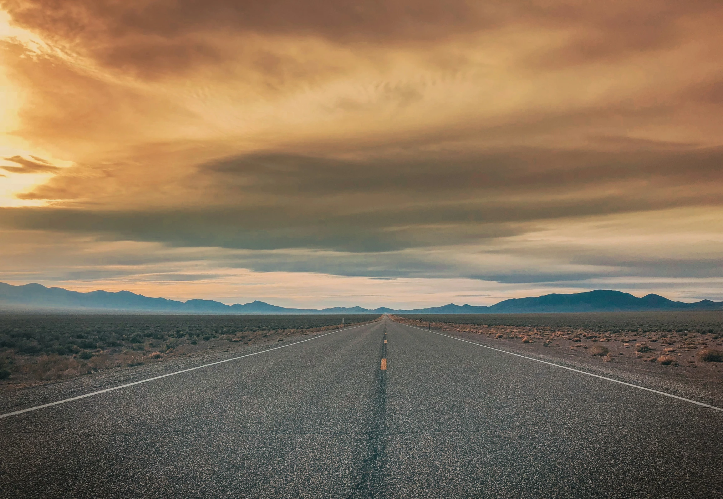 a road that is empty during a cloudy sunset