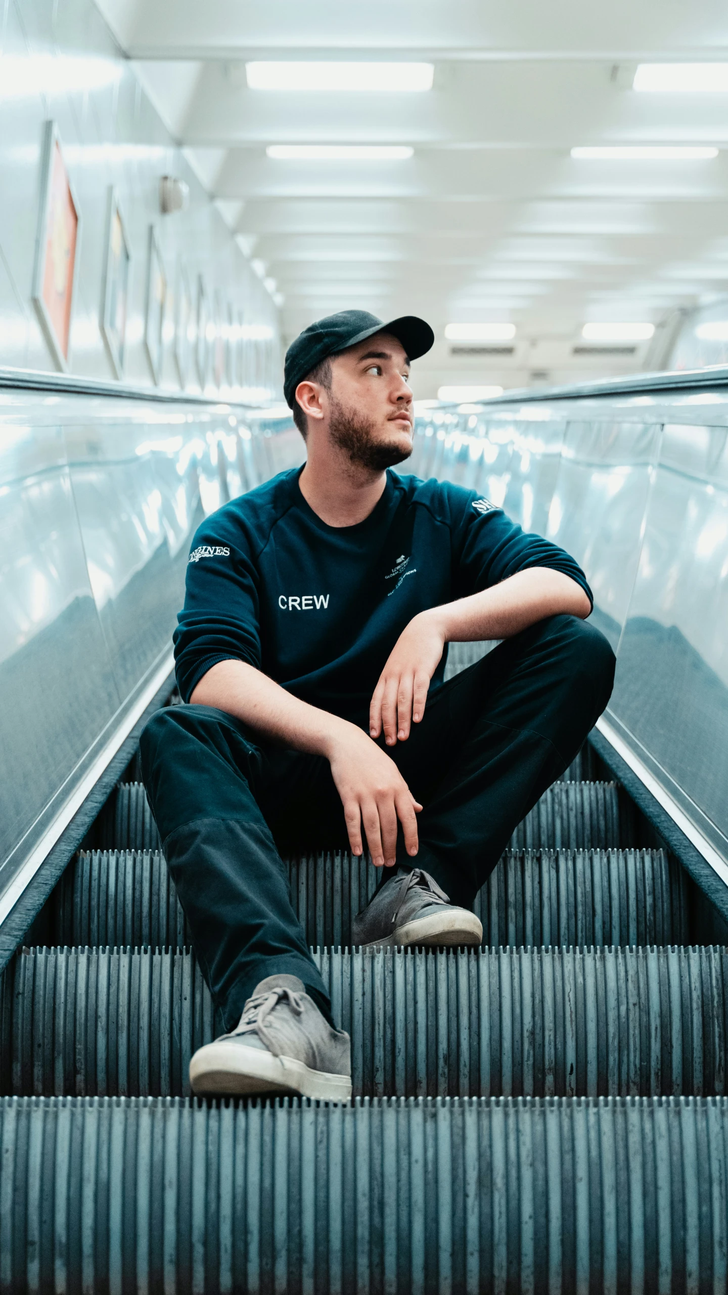 a man wearing a black hat is sitting on an escalator