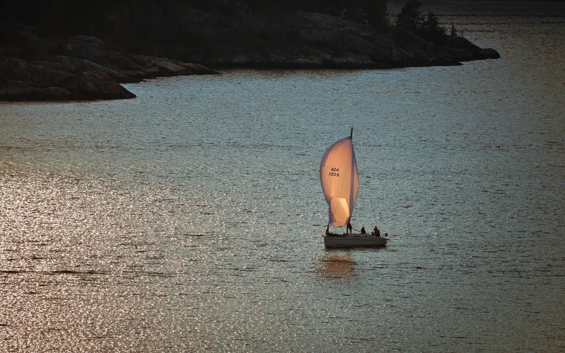 a sail boat with a flag in the middle of a body of water