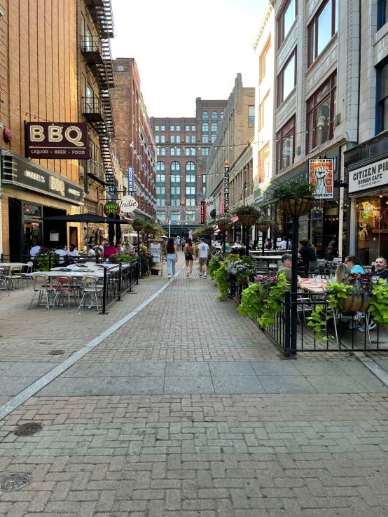 people are walking down a brick street lined with shops