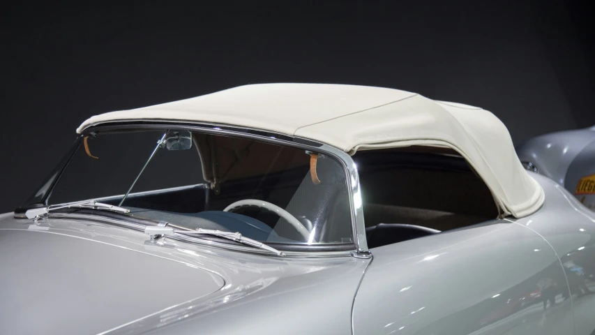 a vintage silver car with a white roof and windshield