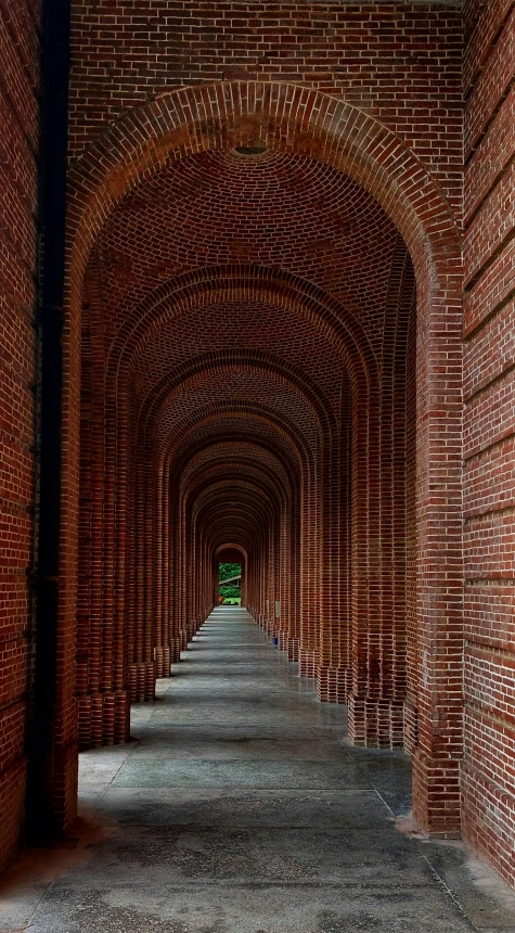 an arched walkway with brick walls and red brick buildings