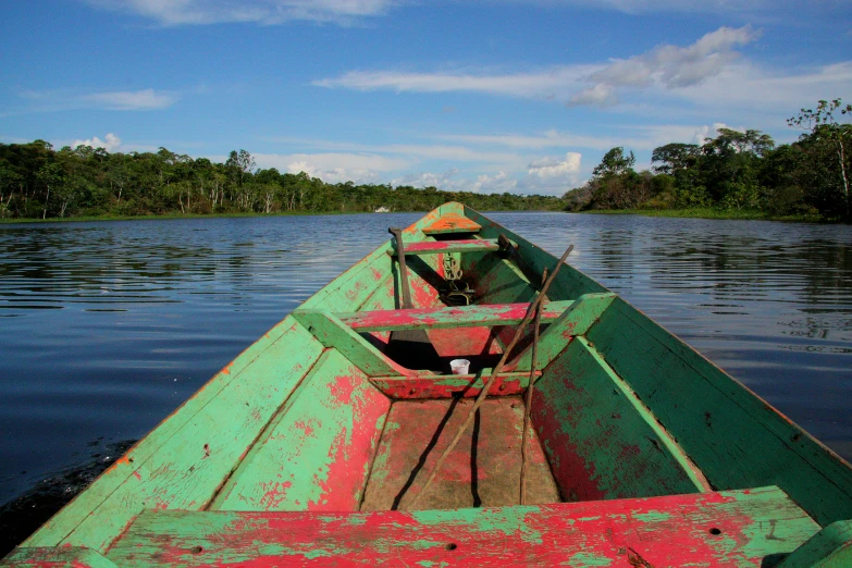 the front end of a green and red boat in a body of water