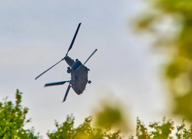 a helicopter flying near a group of trees