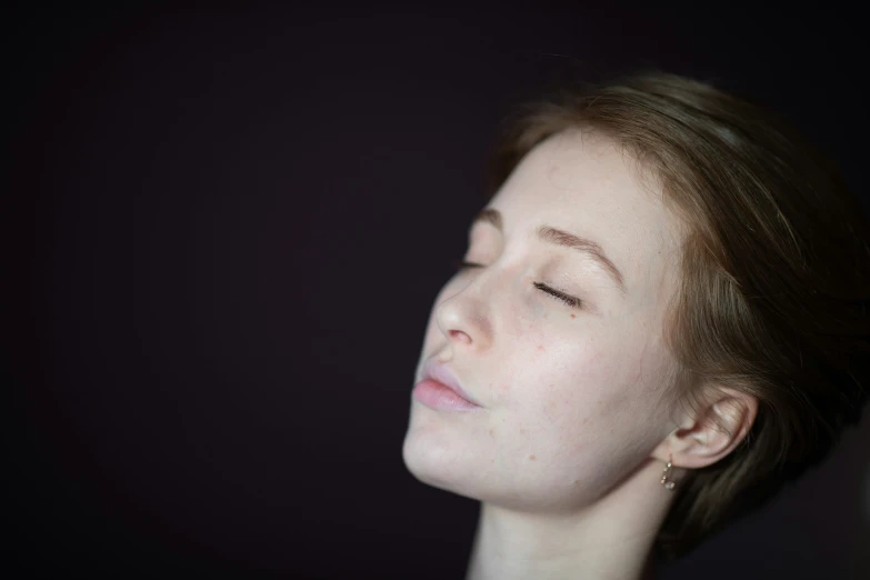 a woman with closed eyes is looking away from the camera