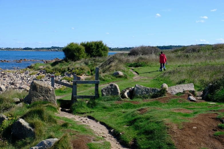 a person walking away from a gate with rocks on the ground