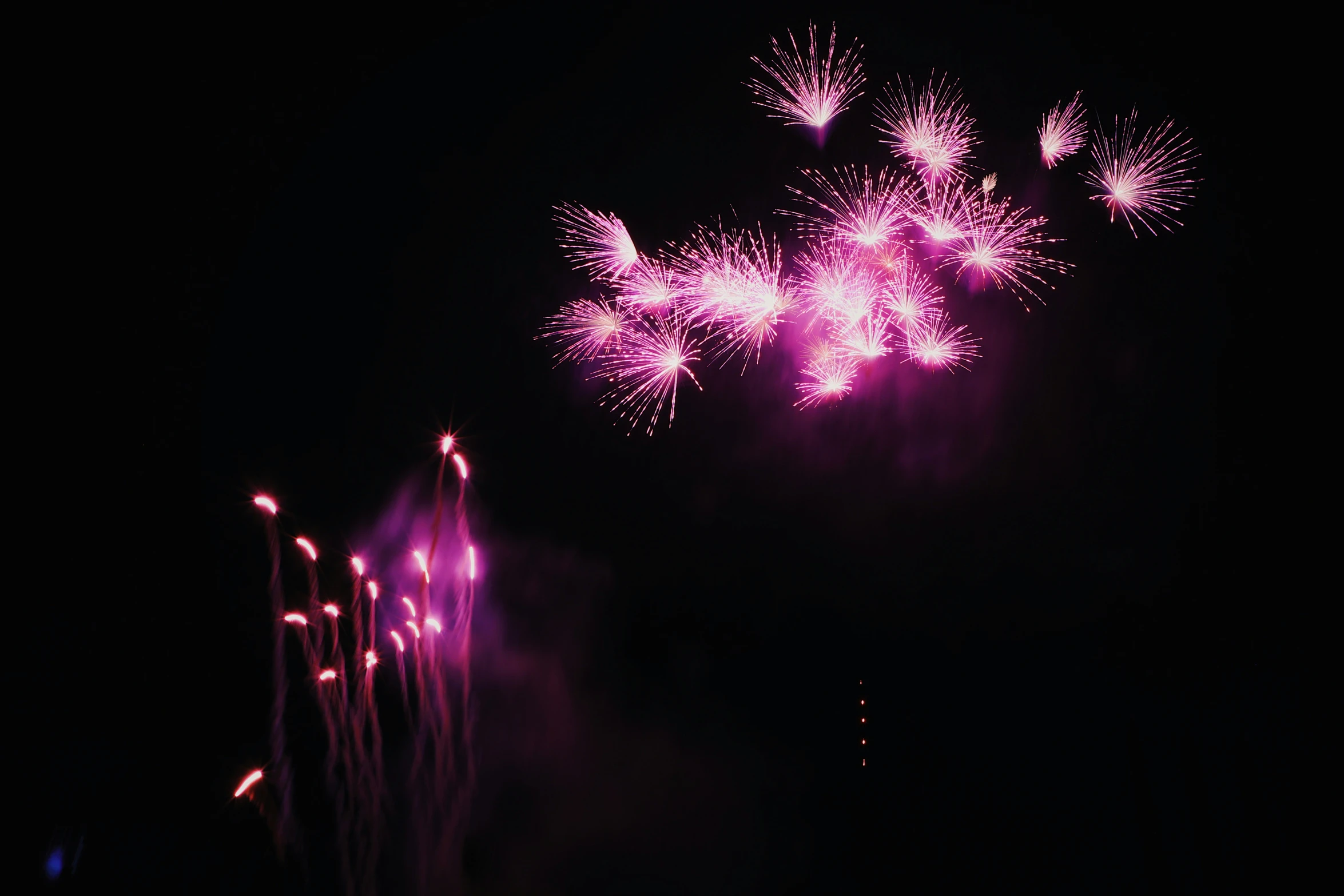 several fireworks with purple lights in the dark sky