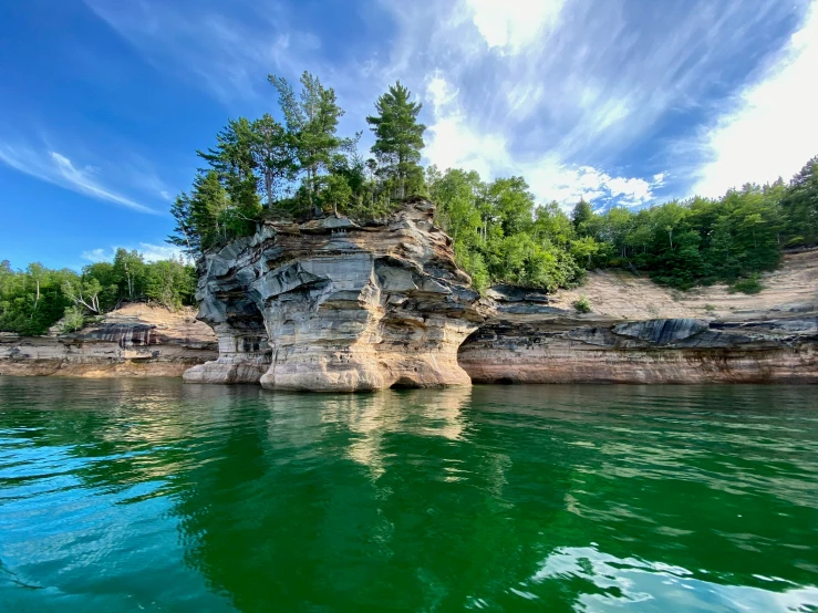 a rock formation in the water with trees on top