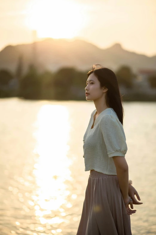 a woman standing next to the water watching soing