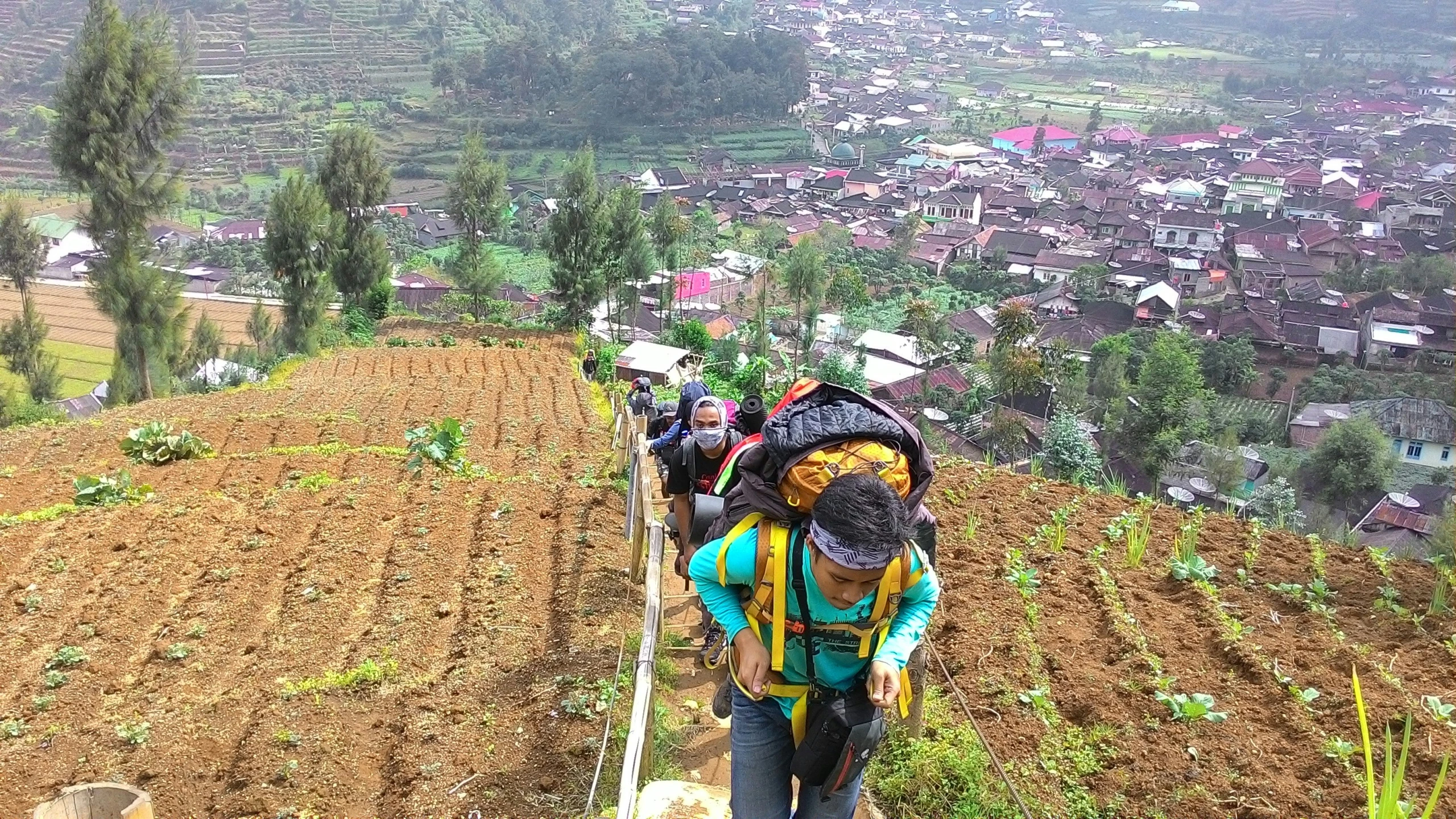 people are walking up a hill on their luggage