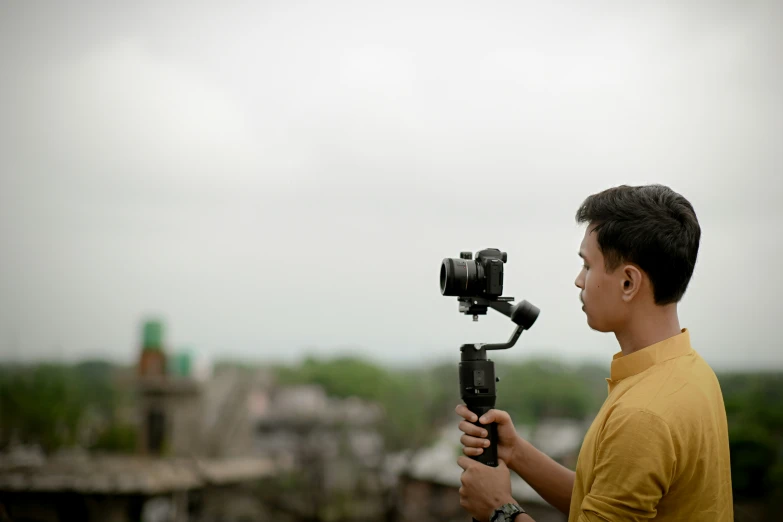 a man standing next to a building holding onto a tripod