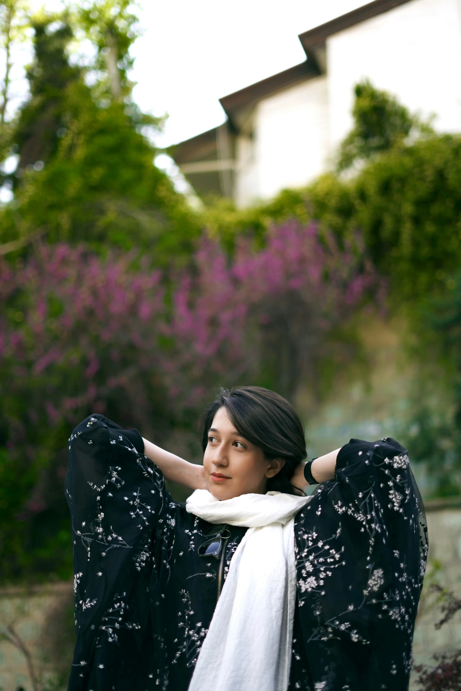 a woman poses in front of purple flowers