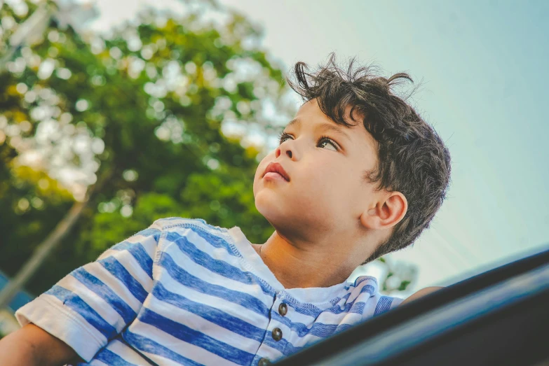 a boy with curly hair looking up into the air