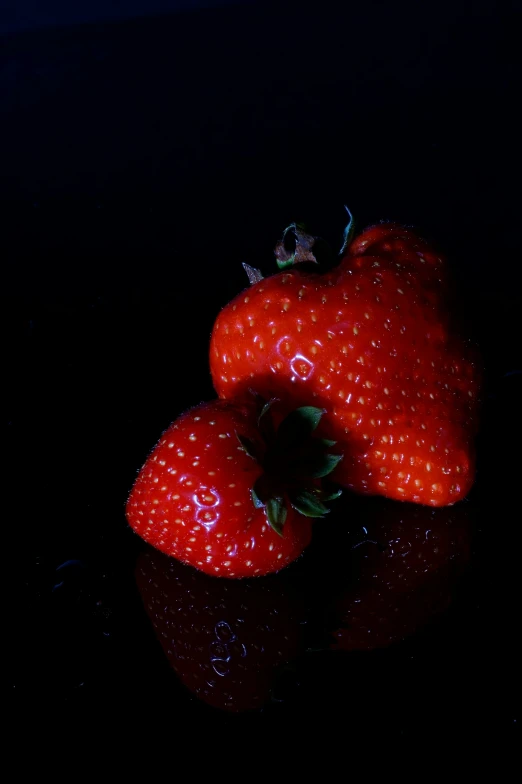 a black table topped with three ripe strawberries