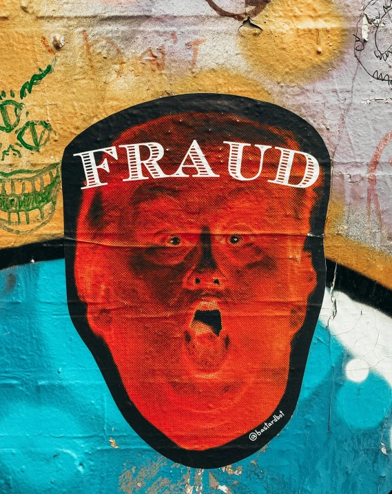 a wall with a drawing of a man's face and the word fraud on it
