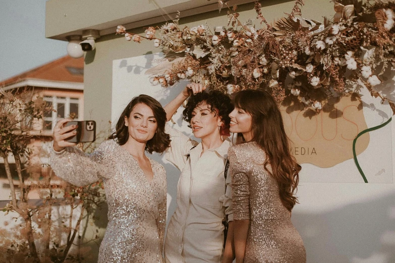 three young ladies taking pictures with cell phones