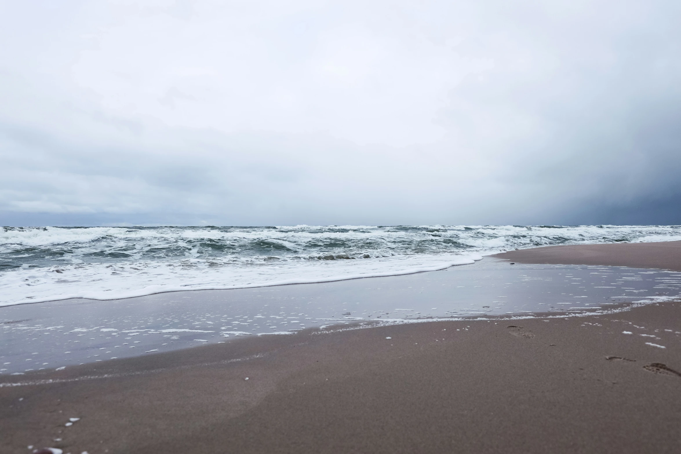 a sandy beach and body of water under a cloudy sky