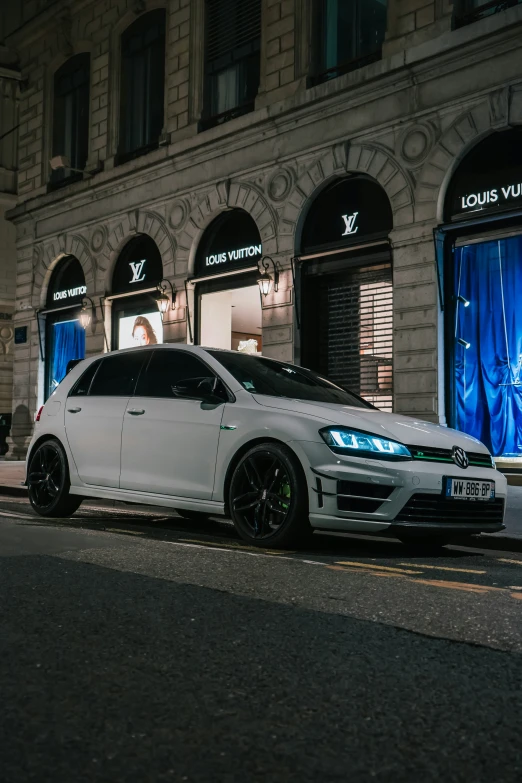 a white car is parked on the street next to some shops