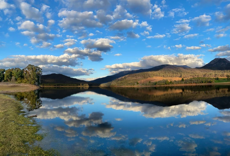 a pond with a mountain and sky reflection in it