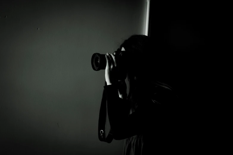 a woman holding a camera up to a pole