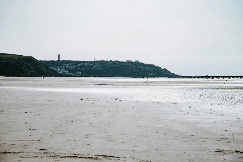 people are walking on the beach and buildings on the hill