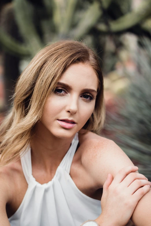 a beautiful young woman sitting in a cactus area