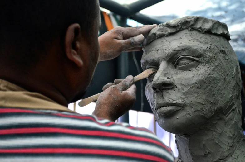 man is creating a sculpture of a face outside