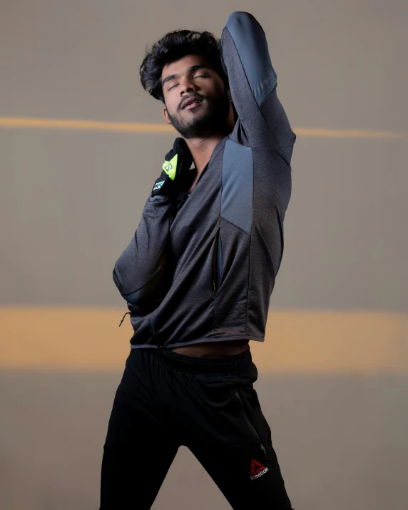 a man wearing gray shirt holding his arms up in the air