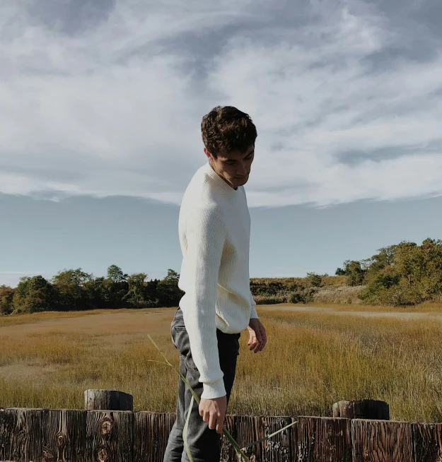 a man standing by a fence with his skateboard in his hand