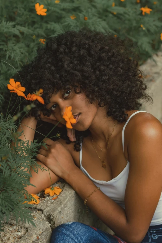 a woman sitting on a curb in the dirt with flowers