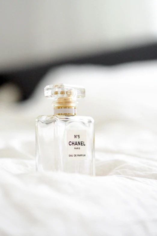 a small bottle sitting on a bed with white sheets