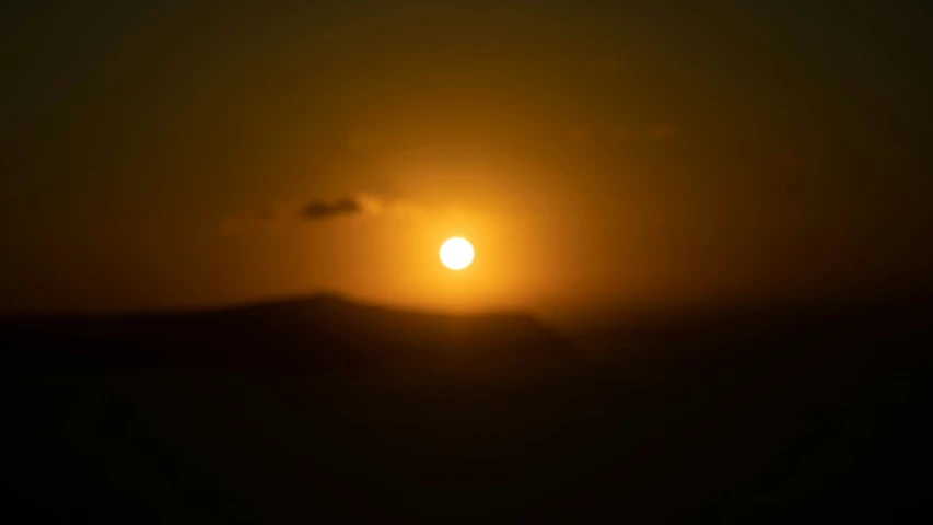 the sun is setting over a large hill in the background