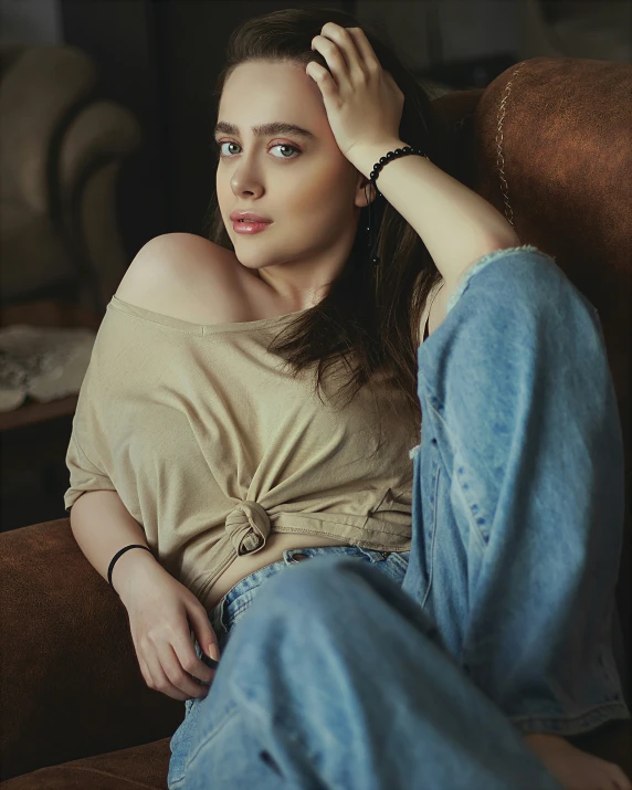 a girl sitting on a couch wearing denims