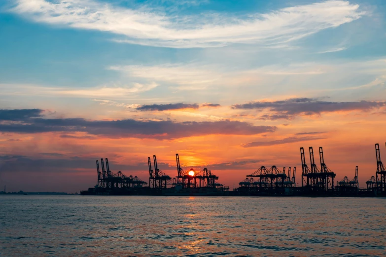 the sun setting behind a harbor filled with boats