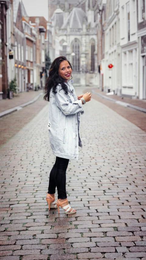 woman in white coat standing on brick road in the rain