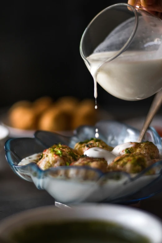 a bowl with food on it and someone pouring sauce