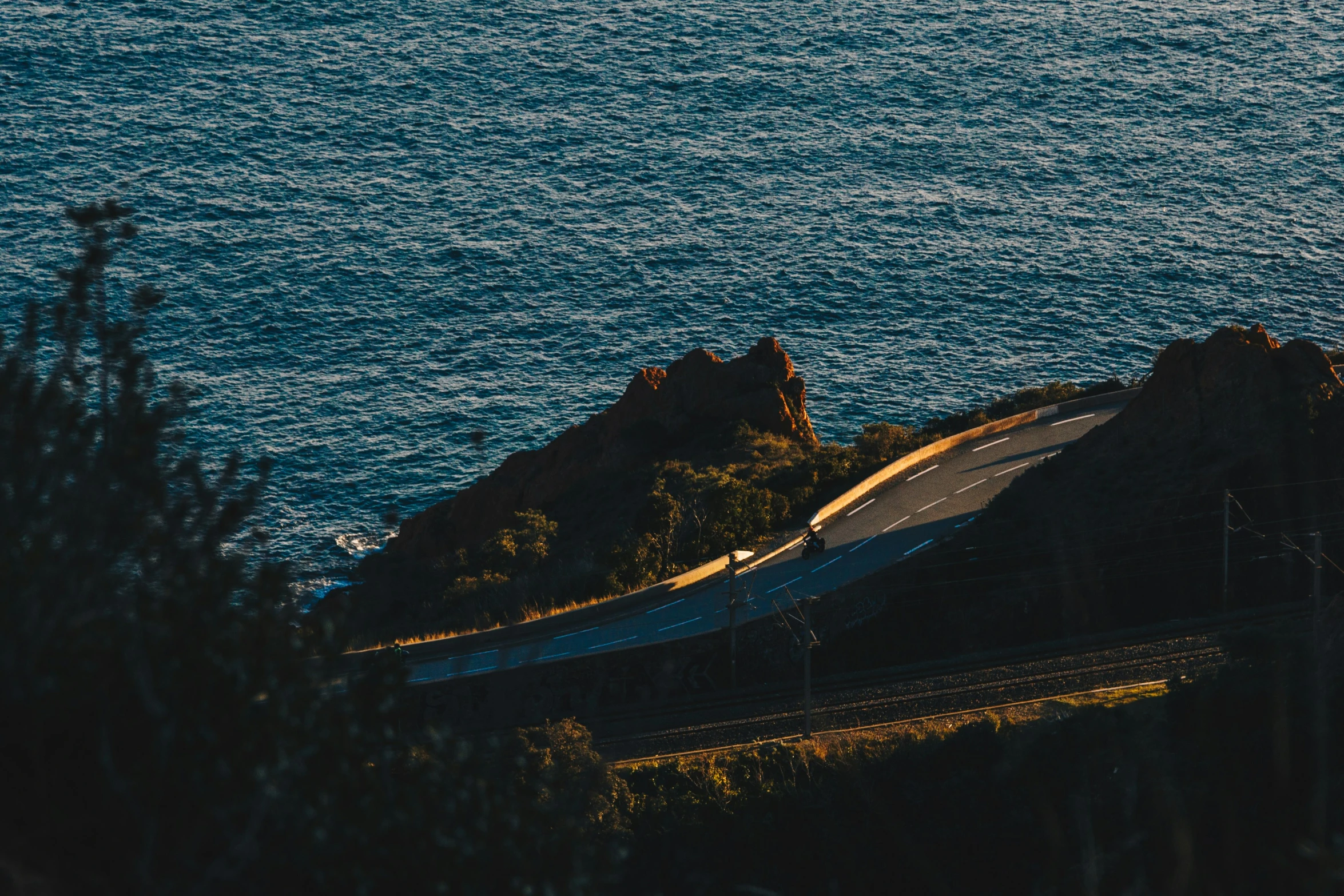 a train on a track with an ocean in the background