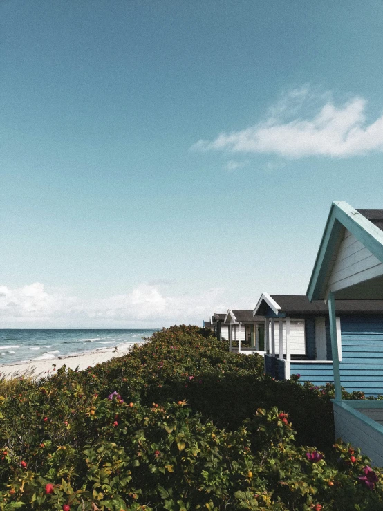 a beach resort next to the ocean under a cloudy blue sky