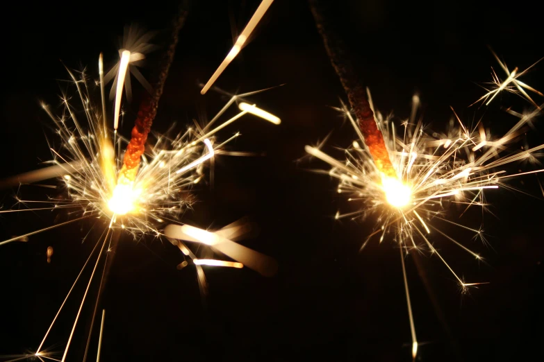 two sparklers are on a black background with many colors