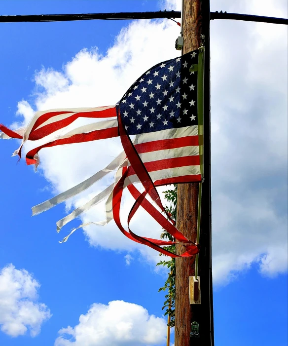 an american flag hangs from a pole on a sunny day