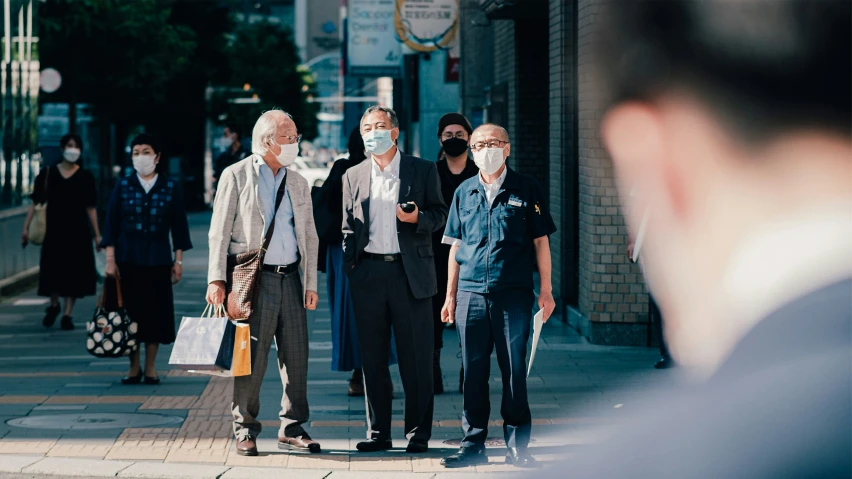 several people wearing masks on the sidewalk