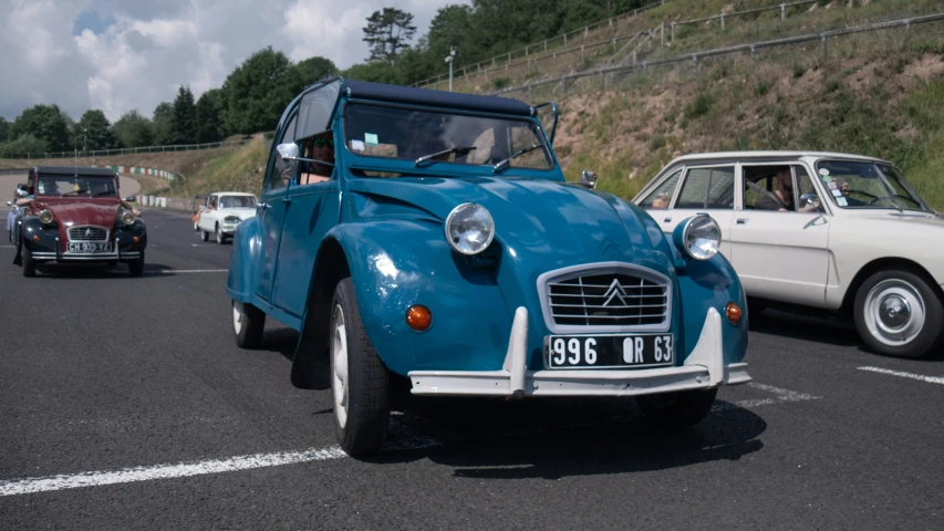 people ride their classic cars on the road