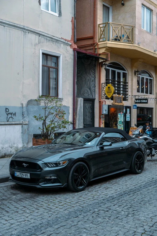 there is a car parked on the cobblestones of this street