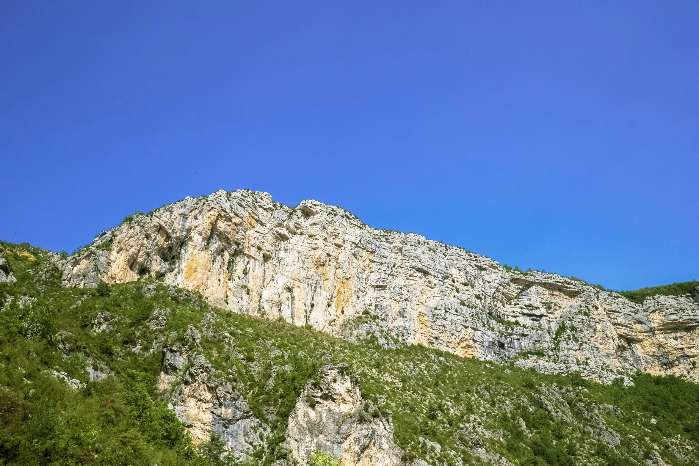 a large mountain that has some green grass on top