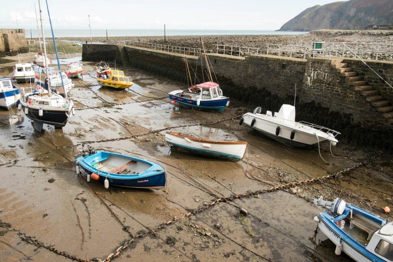 small boats are docked on the muddy shore