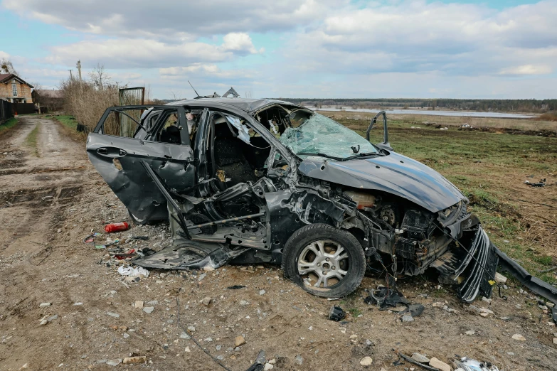 an overturned car on a dirt road near a body of water