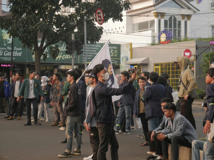 people on the sidewalk are holding flags and a person is standing on the street