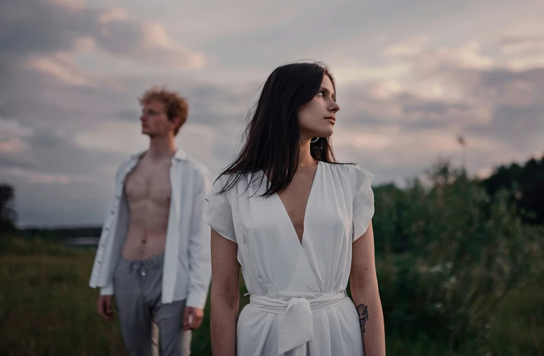 two people standing on a grassy field during sunset